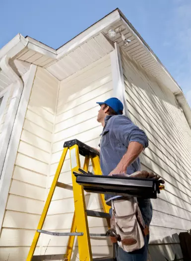 a repair man on a ladder outside a house
